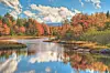 Colorful autumn trees reflecting in a calm river with a partly cloudy sky.