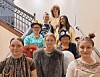 A group of people posing on a staircase indoors, some in costumes and glasses.