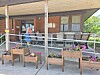 Covered front porch with chairs, tables, and wooden flower planters; a person stands near the doorway.