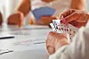 Close-up of hands holding playing cards during a card game at a table.