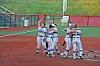 Softball players gather in a celebratory huddle on the infield near home plate.