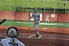 Batter at home plate during a softball game, with catcher foreground and fielder in the background.