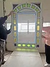 Two people positioning a stained-glass window panel in an interior space.