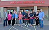 People stand in a line outside Juice and Smoothie Bar holding a red ribbon at a ribbon-cutting event.