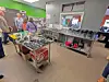 Shoppers inside a store standing near display tables and shelves stocked with products.