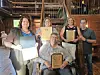 Five people stand indoors holding framed awards and certificates in an industrial-style room.