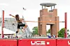 Athlete midair over a high jump bar at an outdoor track and field venue.
