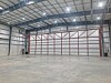 Empty warehouse space with concrete floor, metal walls and ceiling lights.