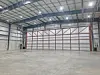 Empty warehouse space with concrete floor, metal walls and ceiling lights.