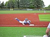Baseball player sliding headfirst into a base on a field.