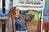 Woman holding a microphone stands in front of a Willandale Golf Cart Sales banner outdoors.