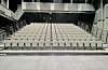 Empty tiered theater seating facing a stage in a dark auditorium.