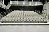 Empty tiered theater seating facing a stage in a dark auditorium.