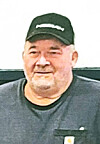 Man in a black Carhartt cap and dark shirt photographed against a plain background.