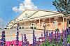 Brick shopping center exterior with parking lot and purple, pink, and red flowers in front.
