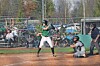 Batter waiting at home plate with catcher crouched behind and umpire standing nearby on a baseball field.