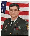 A U.S. Army officer in dress uniform stands in front of an American flag.