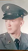 Studio portrait of a young man wearing a military-style uniform and cap.