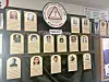 Wall display of framed plaques and portrait panels arranged in rows.