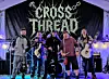 A band performs onstage under a tent with guitars, drums, and stage lighting.