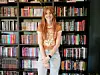 Smiling woman standing in front of a bookshelf filled with books.