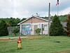 Small building with a mural, fenced yard, red fire hydrant, and American flag on a pole.