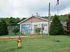 Small building with a mural, fenced yard, red fire hydrant, and American flag on a pole.