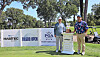 Two golfers standing beside PGA Tour and Toledo Open signs on a golf course.
