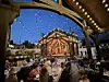 Guests seated at tables in an outdoor restaurant patio beneath string lights at dusk.