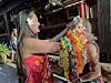 Two women outdoors with bright flower leis at a festive gathering.
