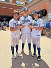 Three people in pinstriped baseball uniforms pose outside a stadium entrance while holding drinks.