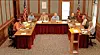 Officials seated around U-shaped tables in a council chamber during a meeting.