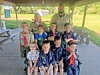 A group of scouts and an adult leader pose together under a park pavilion.