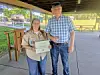 Two people stand under a pavilion holding a certificate and posing for a photo.