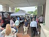 Crowd walking beside vendor tents and display banners under a covered outdoor walkway.