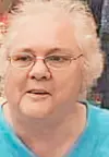 Close-up of a woman wearing glasses and a light blue top.