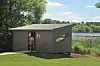 Small dark-gray building near a lake with a person entering through the doorway.