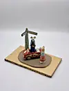 Miniature figurines stand on a small wooden base beside a signpost.