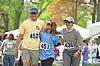 Three runners wearing bib numbers 452, 451, and 436 walk or jog together outdoors.