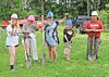 Four people in hard hats pose with shovels on grass at an outdoor ceremony.