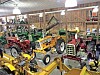 Vintage tractors and yellow farm equipment displayed inside a wooden barn.