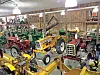 Vintage tractors and yellow farm equipment displayed inside a wooden barn.