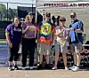 Five people posing outdoors in front of a tent with a 'Streaming at: WDO' sign.