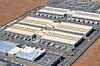 Aerial view of a large industrial complex with several long buildings and parking areas.