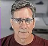Close-up of a man wearing glasses on a video call with a blurred background.