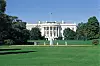 The White House behind a green lawn and fountain under a blue sky.