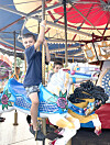 Dos niños sobre un caballo de carrusel azul y blanco bajo un dosel rojo y azul.
