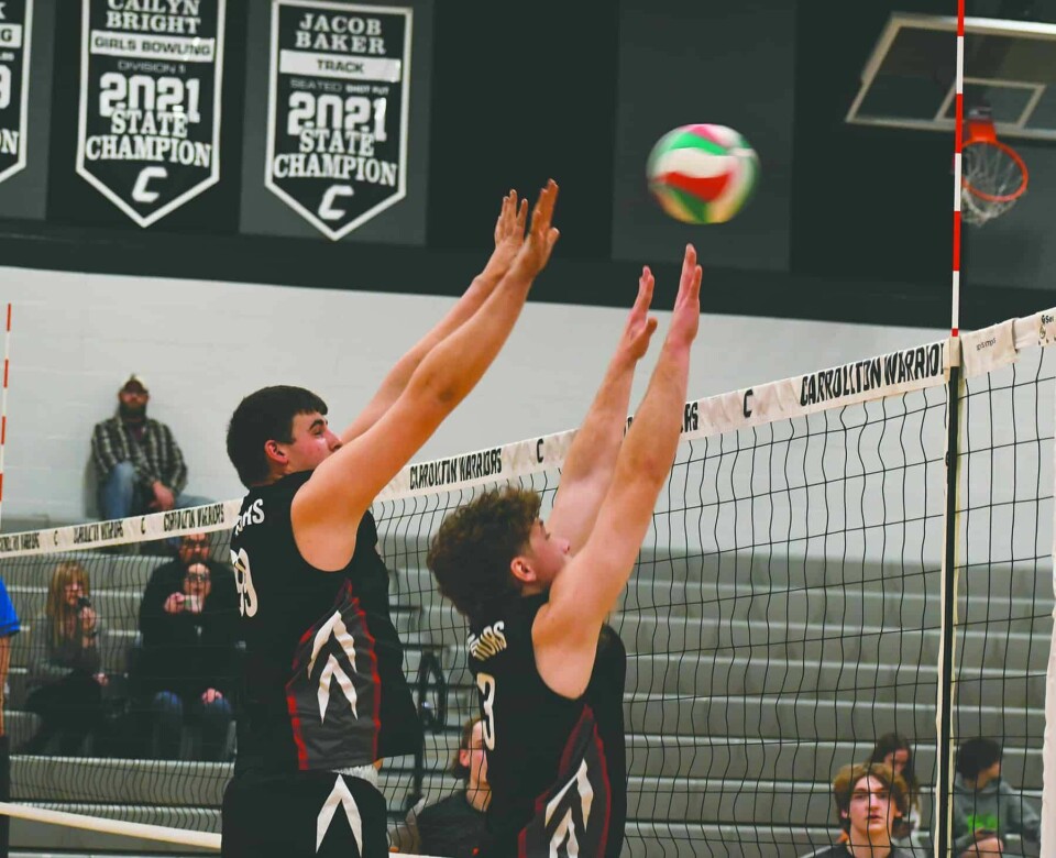 CCM/Dan RiesCarrollton’s Ty Pridemore (left) and Carter Higgins go for a block against the Howland Tigers. The Warriors won in four sets.