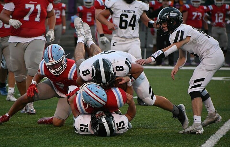Carrollton defenders Gunnar Burgett (8) and Dillon Naylor (15) sandwich Alliance quarterback Brendan Zurbrugg early in the contest Friday. Warrior Ryan Kiko (32) is at right.