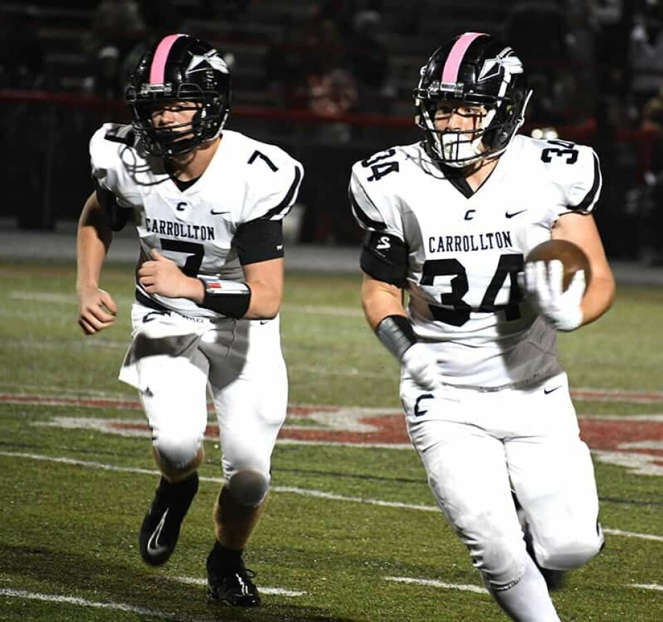 CCM/Dan Ries Warrior quarterback Jacob Whitmore (7) leads runningback Levi Crider (34) around the end during Friday’s rivalry game at Robert Hines Stadium.